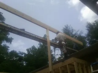 Carpenter setting a ridge beam over a new addition frame — Ice Dam Removal by Roofing Brothers in Kendalia
