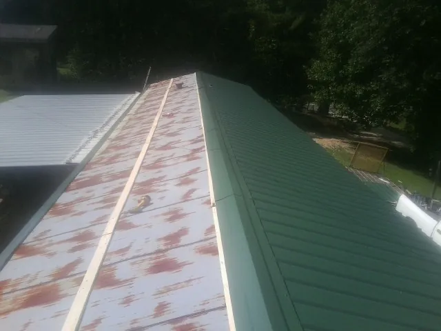 Old rusted panels beside newly installed green metal roofing — Wind Damage Roof Repair by Roofing Brothers in Kendalia