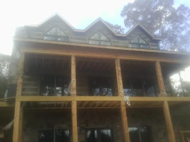 Dormers and porch framing on a large log home under construction — Roof Coating work by our crew in Kendalia