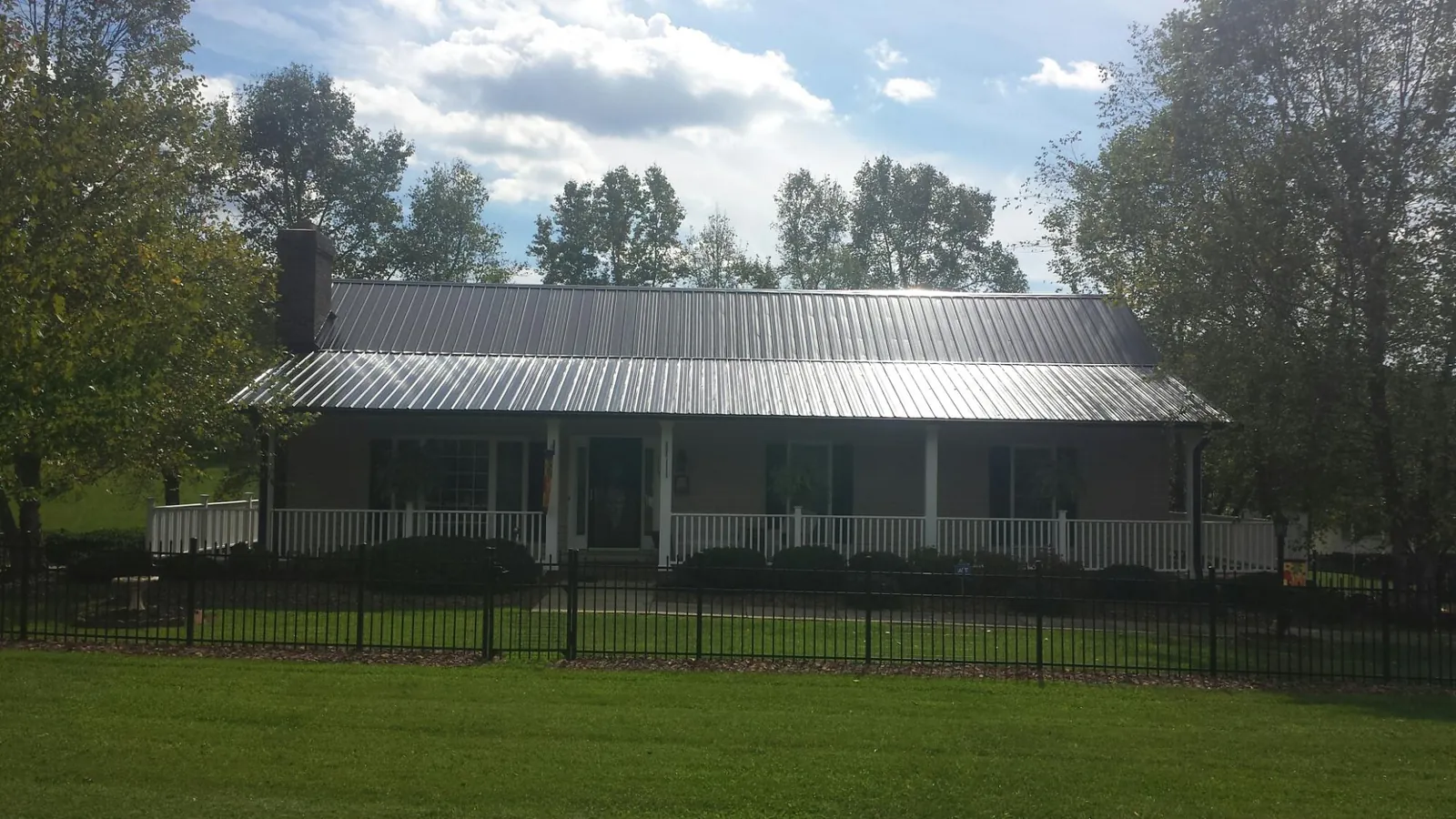 Gray metal roof on a brick ranch with a full width front porch — Gutter Guard Installation work by our crew in Kendalia